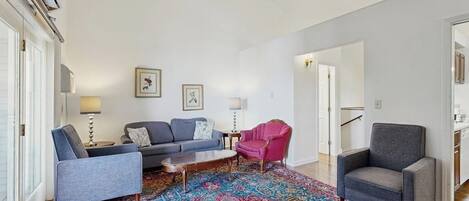 Un salon comprenant un canapé, des fauteuils, une table basse et un tapis à motifs.