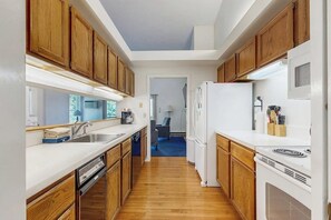 Eine kleine Küche mit Holzausstattung, Spüle, Kühlschrank und Herd.