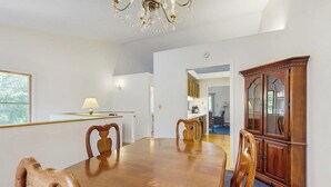 Een eetgedeelte met een houten tafel, stoelen, een kroonluchter en een houten kast.