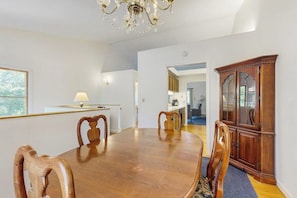 Ein Essbereich mit einem Holztisch, Stühlen, einer Chandelier und einem Holzschrank.
