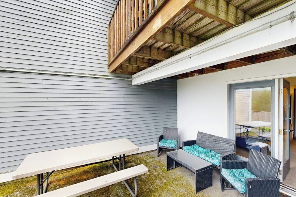 A patio area with a table and chairs, a covered seating area, and a view of the house.