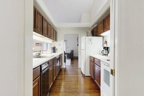 Une cuisine étroite avec des meubles de rangement en bois, un lave-vaisselle et un réfrigérateur.