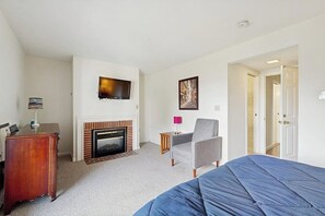 Ein Hotelzimmer mit Bett, Fernseher, Kamin, Stuhl und Schreibtisch.