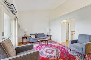 A spacious living room with a large rug, a sofa, a chair, and a coffee table. - Convenient Dog-Friendly Townhouse w/Bay Views, Fast WiFi, A/C, Gas Grill, & More (Bar Harbor)