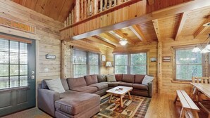 A log cabin interior with a sectional sofa, a wooden dining table, and a bench.