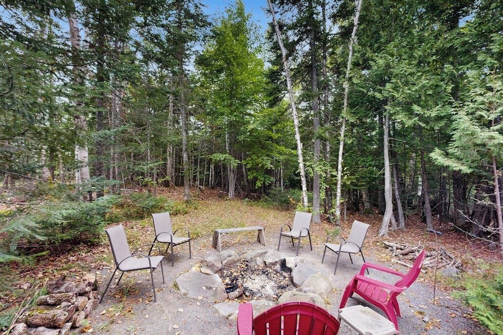 Un décor forestier avec un foyer et des chaises disposées autour.