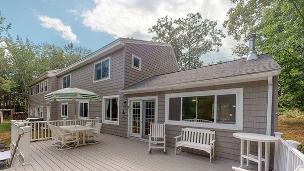 Une maison à deux étages dotée d’une terrasse, d’un espace salon extérieur et d’une cheminée.
