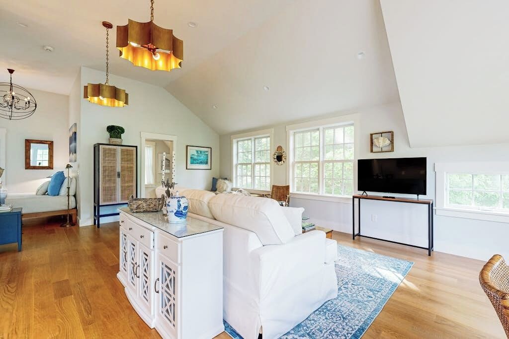 A spacious living room with a white sofa, a coffee table, a TV, and a large window.