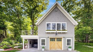 Een twee verdiepingen tellend huis met garage, overdekte veranda en een kleine tuin.
