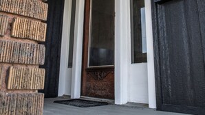 A wooden door with a glass panel, a brick wall, and a white door frame.