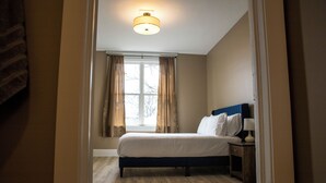 A bedroom with a bed, a nightstand, a lamp, and a window with curtains.