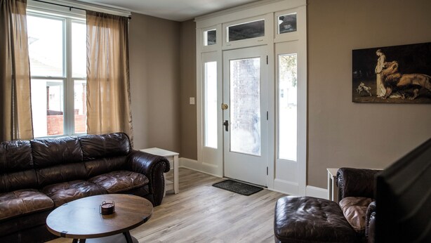 A living room with a leather sofa, a coffee table, a door with glass panels, and a painting on the wall.