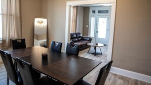 A dining area with a dark wooden table, black chairs, a round coffee table, and a brown leather sofa.