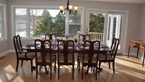 A dining room with a large wooden table, six chairs, and a chandelier. - Great home with water view - one house from harbor - washer/dryer & dog-friendly (Camden)