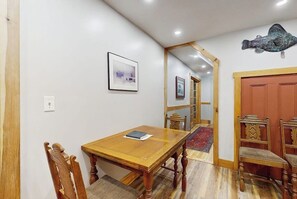 Ein Essbereich mit einem Holztisch und Stühlen, einem gerahmten Bild an der Wand und einem Spiegel, der den Raum widerspiegelt.