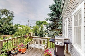 Une terrasse en bois avec un barbecue, des plantes en pot et un banc.