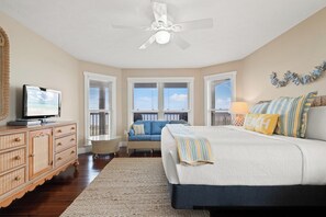 A bedroom with a bed, a television, a ceiling fan, and a view of the sky through windows. - Beach House - Mutual Fun (Port St. Joe)