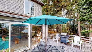 En terrasse med et bord, stole, grill og swimmingpool.