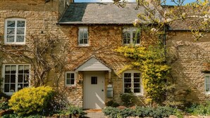 Una casa de piedra con puerta central, ventanas y un pequeño porche.