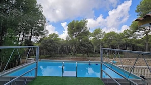 Ein Schwimmbecken mit Metallgeländern, umgeben von Bäumen und blauem Himmel.