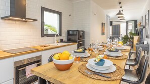 Een moderne keuken met witte bakstenen muren, een houten aanrecht en een eethoek met een lange tafel gedekt voor een maaltijd.