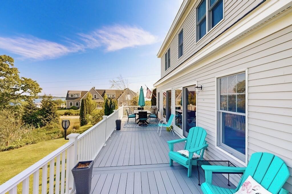 Une terrasse couverte, aménagée avec du mobilier d’extérieur, un pergolas et une vue sur les maisons voisines.