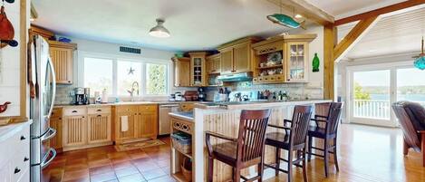 A spacious kitchen with wooden cabinets, a central island, and a dining area with chairs.