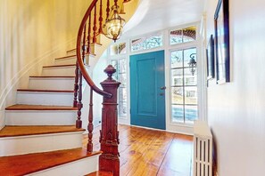 Un escalier avec des marches en bois et une rampe en bois, menant à une porte dotée d’un cadre bleu.