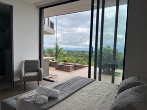 A modern bedroom with a large window, a bed, a chair, and a view of a lush landscape. - Villa with infinity pool and 180° views Filandia (Filandia)