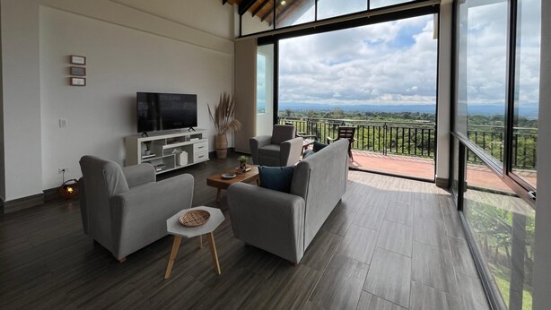 A spacious living room with a large TV, comfortable seating, and a balcony with a scenic view. - Villa with infinity pool and 180° views Filandia (Filandia)