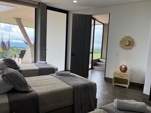A modern hotel room with two beds, a small side table, and a view of the outdoors. - Villa with infinity pool and 180° views Filandia (Filandia)