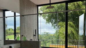 A modern bathroom with a large mirror, a built-in sink, and a view of a balcony with a brick floor. - Villa with infinity pool and 180° views Filandia (Filandia)
