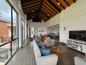 A modern living room with a sofa, coffee table, TV, and kitchen area. - Villa with infinity pool and 180° views Filandia (Filandia)