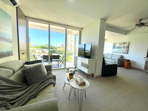 A modern living room with a sofa, a coffee table, a TV, and a balcony with a view. - Apt with Terrace, Views, Pools and Beach | Zazue (Santa Marta)