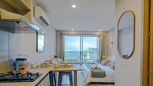Ett modernt hotellrum med kök, matplats och ett stort fönster med utsikt över staden.