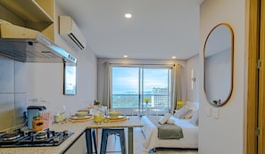 A modern hotel room with a kitchen, dining area, and a large window with a city view. - Panoramic Loft with Balcony at Santa Marina, 21st (Santa marta)