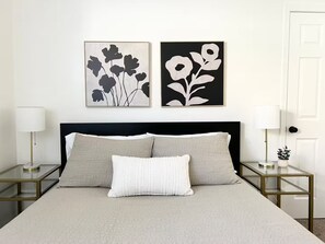 A bed with a black headboard, two bedside tables with lamps, and two wall-mounted artworks. - Cozy Home with HotTub, Patio, Grill & Park Views (Gilbert)