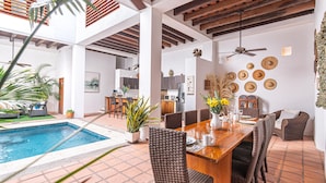 A spacious indoor area with a pool, dining table, wicker chairs, and a ceiling fan. - Room in Colonial House with Pool and Rooftop (Santa Marta)
