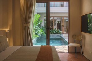 Une chambre avec un lit, une chaise, une vue sur une piscine extérieure et une porte-fenêtre coulissante.