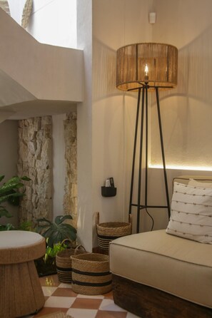Une pièce chaleureuse avec un canapé, une lampe, des paniers en osier et un mur en pierre.