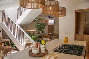 Une cuisine moderne équipée d’une cuisinière à gaz, de chaises en bois, d’une table à manger et d’un escalier.