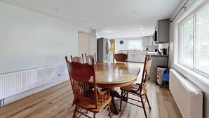 Una cocina moderna con armarios blancos, una mesa de comedor con sillas y un amplio ventanal que proporciona luz natural.