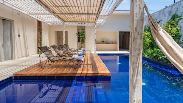 A poolside area with lounge chairs, a wooden deck, and a clear blue pool. - Apt. Suite with pool in colonial house  Downtown (Santa Marta)