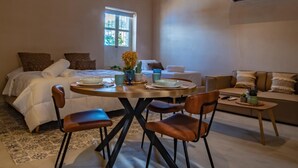 A spacious room with a bed, a dining table with chairs, a sofa, and a window providing natural light. - Apt. Suite with pool in colonial house  Downtown (Santa Marta)