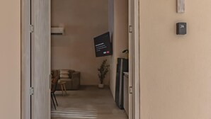 A hallway with a door leading to a room, a wall-mounted TV, and a thermostat. - Apt. Suite with pool in colonial house  Downtown (Santa Marta)