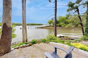 A bench overlooking a river with a wooden bridge, surrounded by trees and a gravel path. - Stunning riverfront home, hot tub, BBQ, and washer & dryer (Edgecomb)