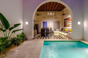 A pool area with a checkered floor, a dining area with chairs and a table, and a kitchen in the background. - Casa Paguro, a charming republican oasis (Santa Marta)
