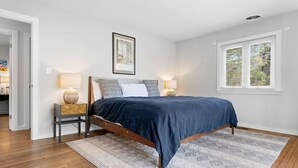 A bedroom with a bed, bedside lamps, a rug, and a window. - Evelyn's River Front Retreat- Spacious House with Modern Comforts and Nature (Cushing)