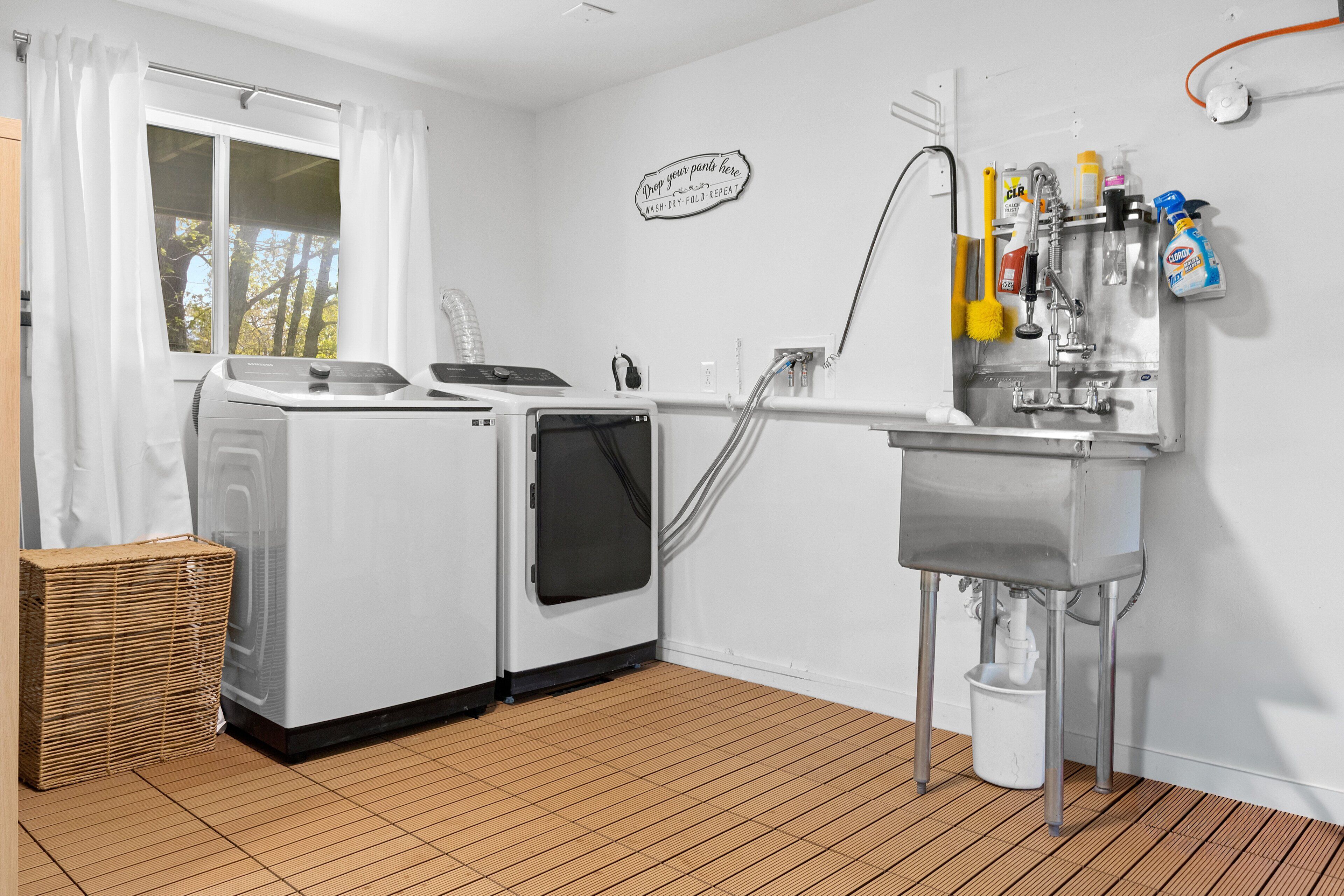 Een wasserette met een wasmachine, droger en een spoelbak met schoonmaakmiddelen.