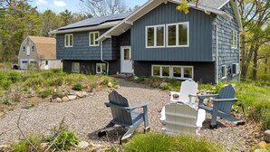 A two-story house with a gravel driveway and outdoor seating. - Evelyn's River Front Retreat- Spacious House with Modern Comforts and Nature (Cushing)